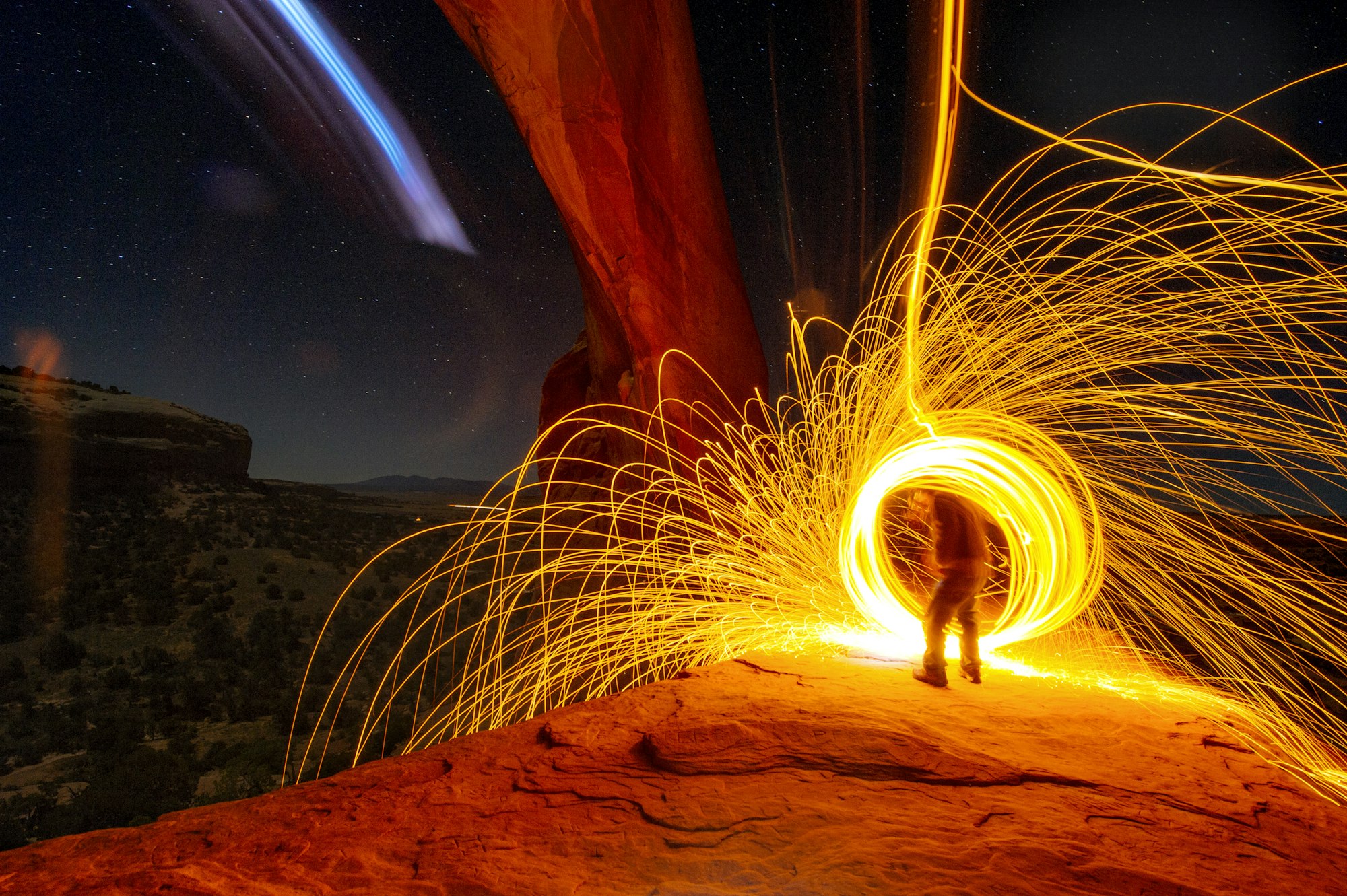 Mature man creating long exposure light painting on cliff side, Moab, Utah, USA